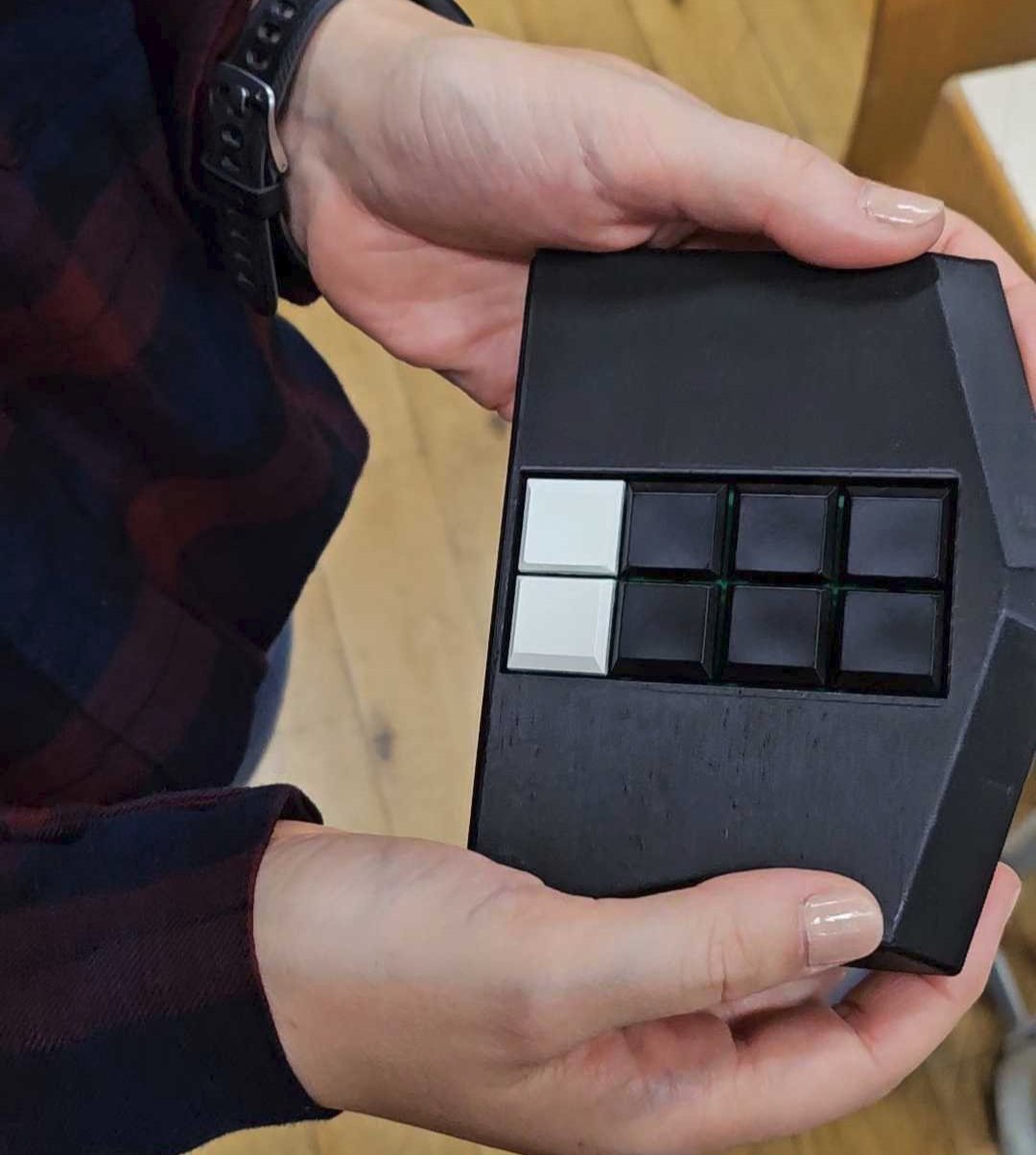 Julia is holding a black version of the Meta Braille keyboard.